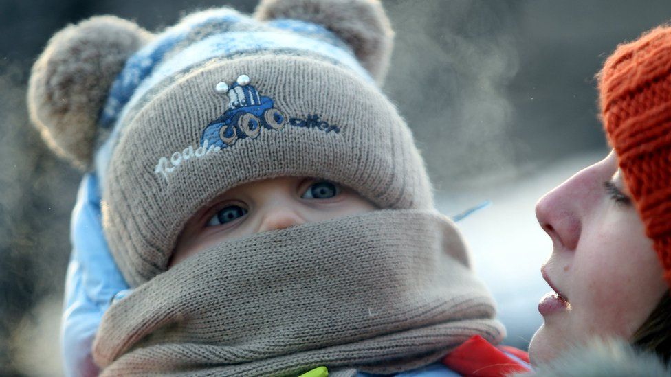 young mother with her baby walks in the cold in Bishkek