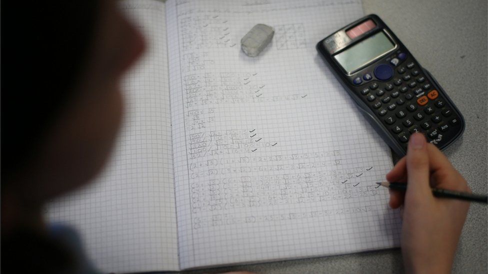 A student doing maths in their book with a calculator