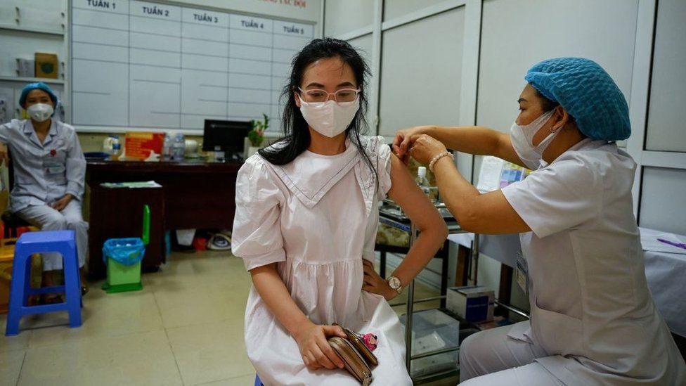 Женщина (C) получит вакцину против коронавируса Moderna Covid-19 в начальной школе в Ханое 27 июля 2021 года
