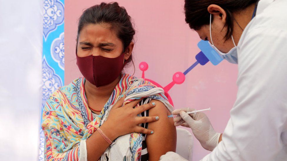 Медицинский работник вводит дозу вакцины Covid-19-19-19 женщине в Нью-Дели.