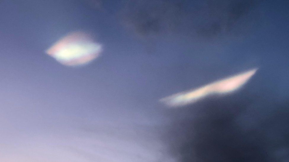 Two smooth nacreous cloud shimmering in the night sky