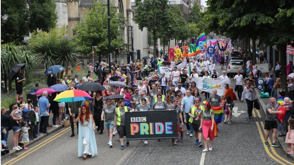 Marchers hold a banner with BBC Pride written on it as they pass St Anne's Cathedral in Belfast