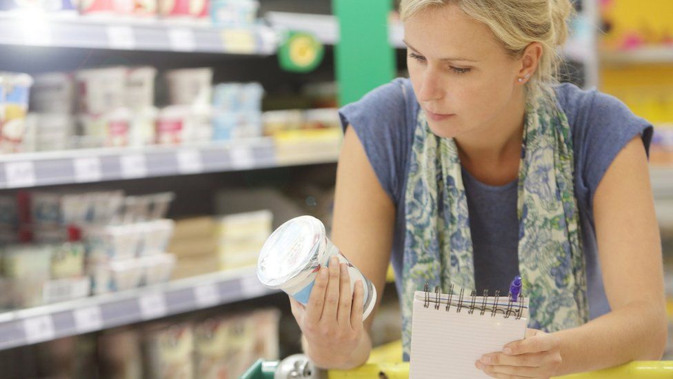 Woman looking at yoghurt to buy in supermarket
