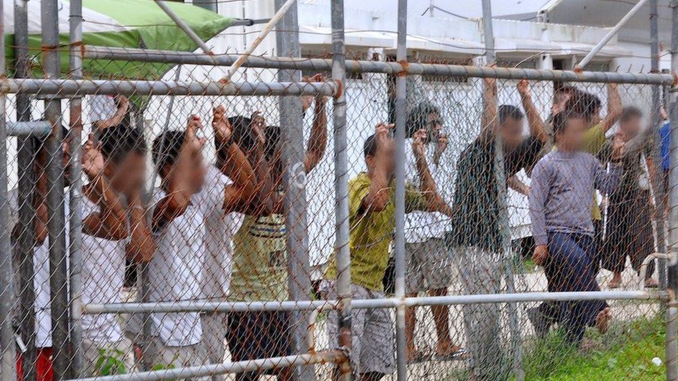 Asylum-seekers look through a fence at the Manus Island detention centre in Papua New Guinea 21 March 2014.