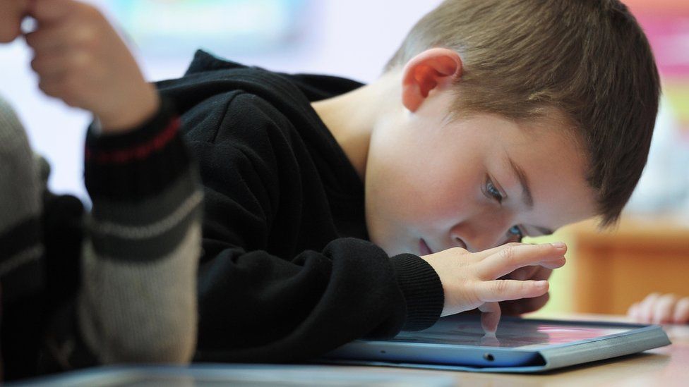 A boy looks at a tablet
