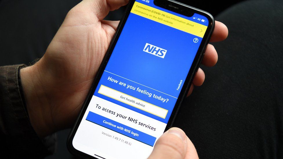 Hands seen holding a smartphone displaying the NHS Covid app