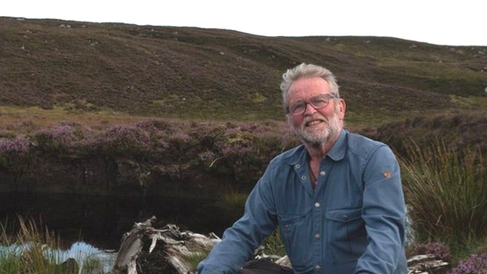 Cormac Ó hÁdhmaill sitting in a peatland