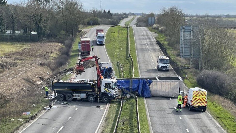 Contents of overturned lorry being moved to another lorry