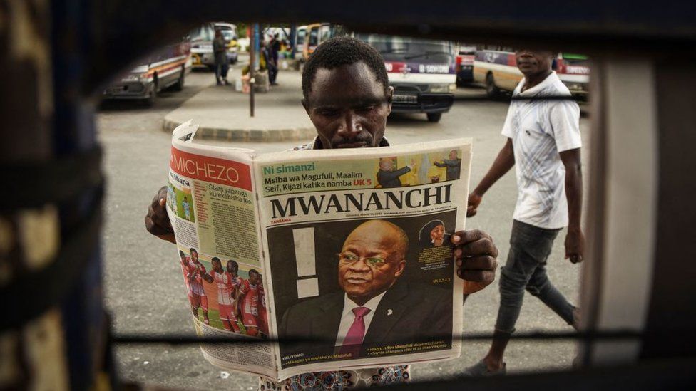 Мужчина читает газету с заголовком о смерти президента Танзании Джона Магуфули в Дар-эс-Саламе 18 марта 2021 года.