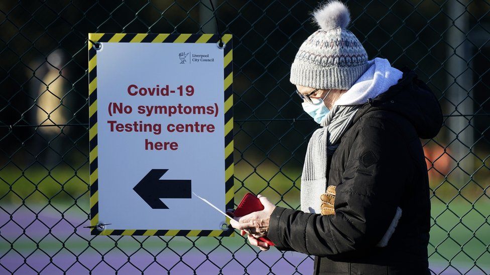 Members of the public queue at a mass Covid-19 testing site in the Liverpool Tennis centre at Wavertree Sports Park on January 05, 2021 in Liverpool, United Kingdom