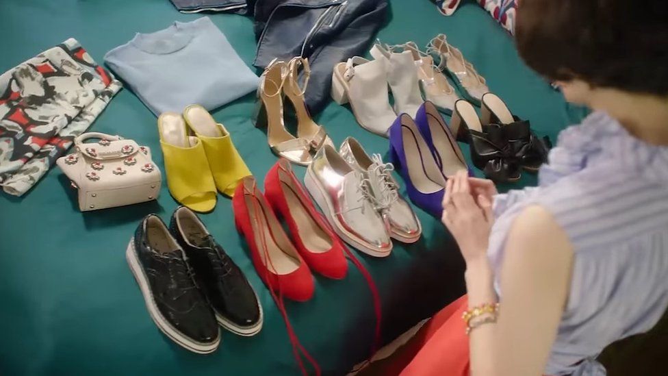 Women inspecting shoes and clothes on her bed