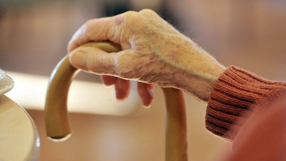 Older person's hand on walking stick