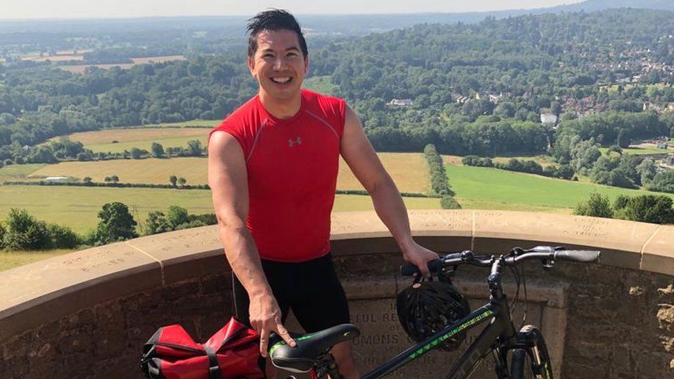 Bruce Chin, who splits his time between Epson Downs in Surrey and San Francisco, pictured in cycling gear holding a bike during a bike ride in the UK