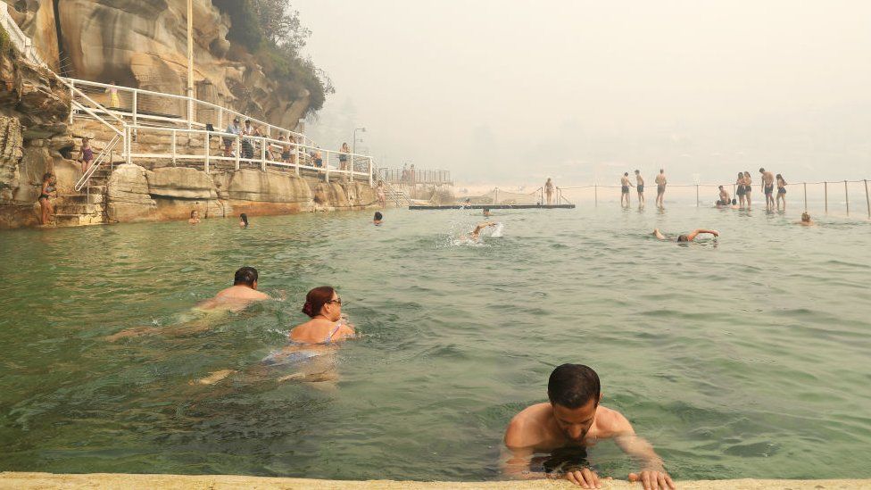 Swimmers at a Sydney beachside pool amid the smoke on Tuesday morning