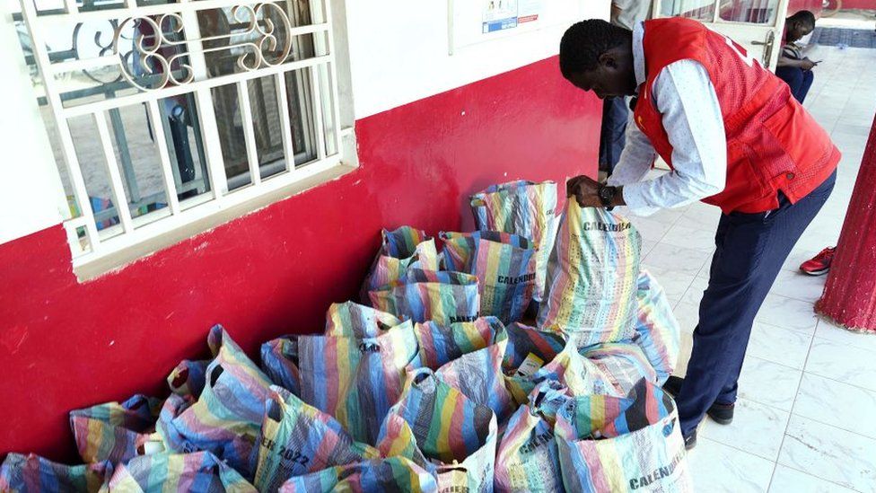 Сотрудник Красного Креста Гамбии просматривает мешки с собранными сиропами от кашля в Банжуле.