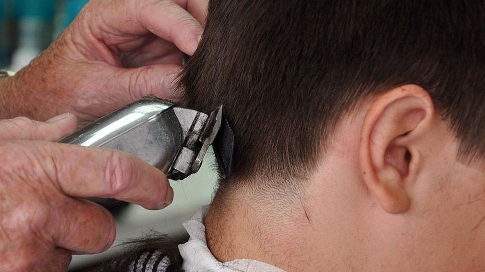 Barber cuts man's hair