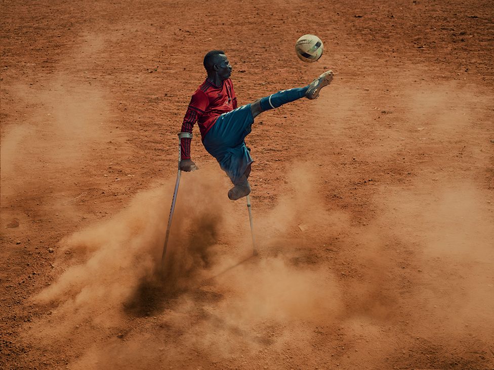An amputee football player kicks a ball
