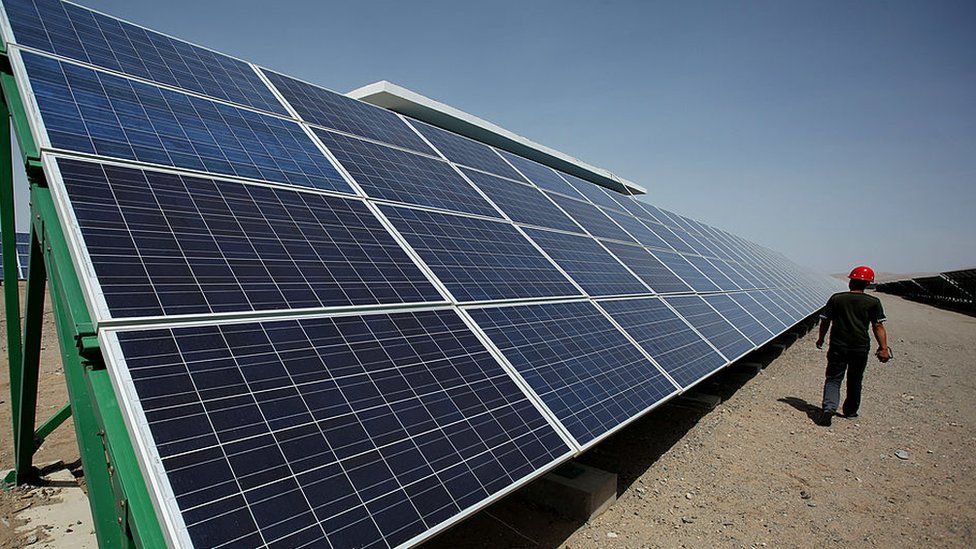 A Chinese worker walks between solar panels in Dunhuang, in China's northwest Gansu Province