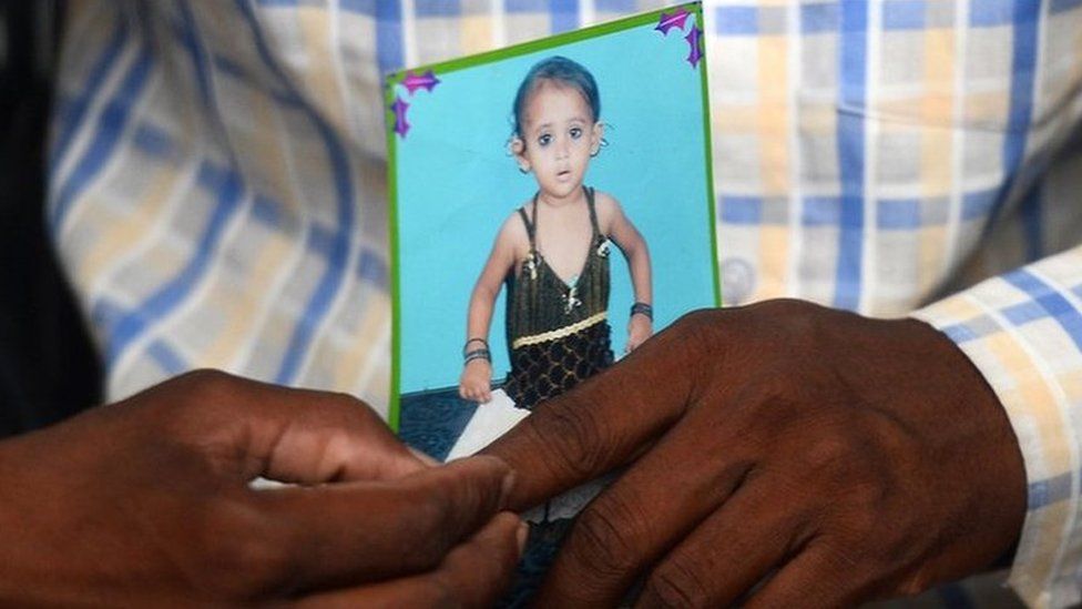 Mohamed Zahid hold a photo of his five-year-old dauhter, Khushi, in a black dress