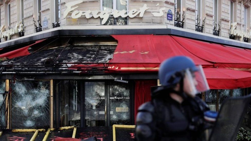 A French riot police officer stands in front of the gutted Le Fouquet's restaurant in Paris. Photo: 16 March 2019