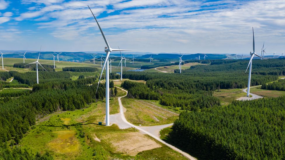 Aerial drone view of turbines at a large onshore windfarm on a green hillside, Pen y Cymoedd, Wales