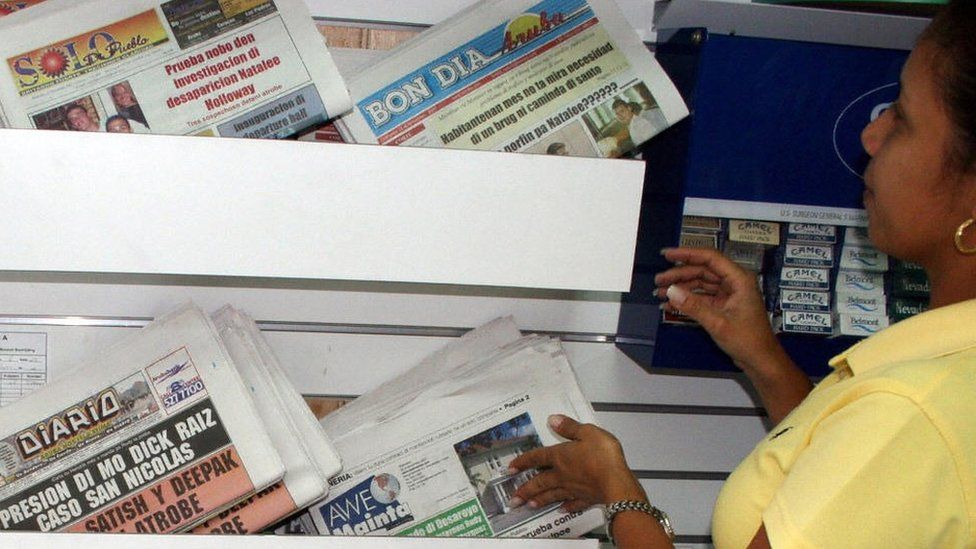 A woman looks headlines in the Aruba press