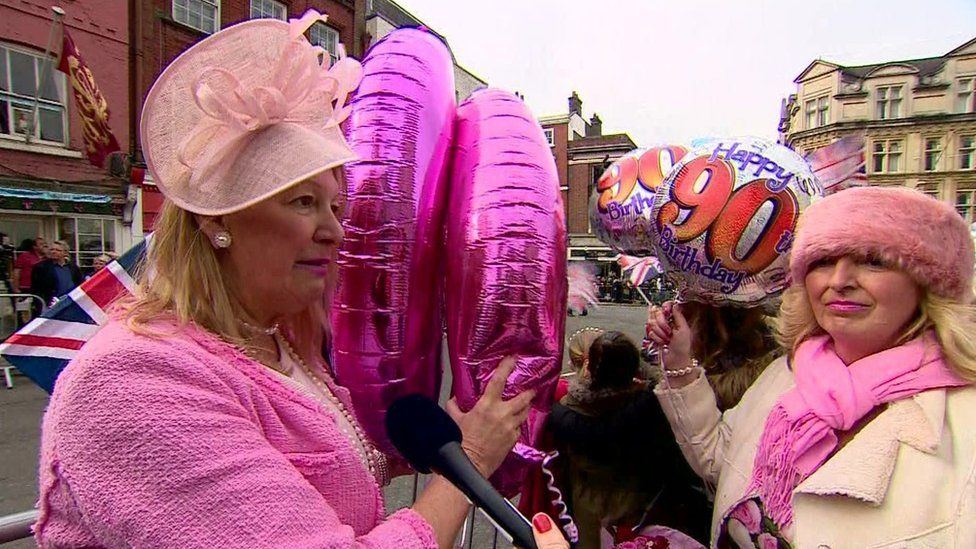 Two ladies dressed in pink holding balloons