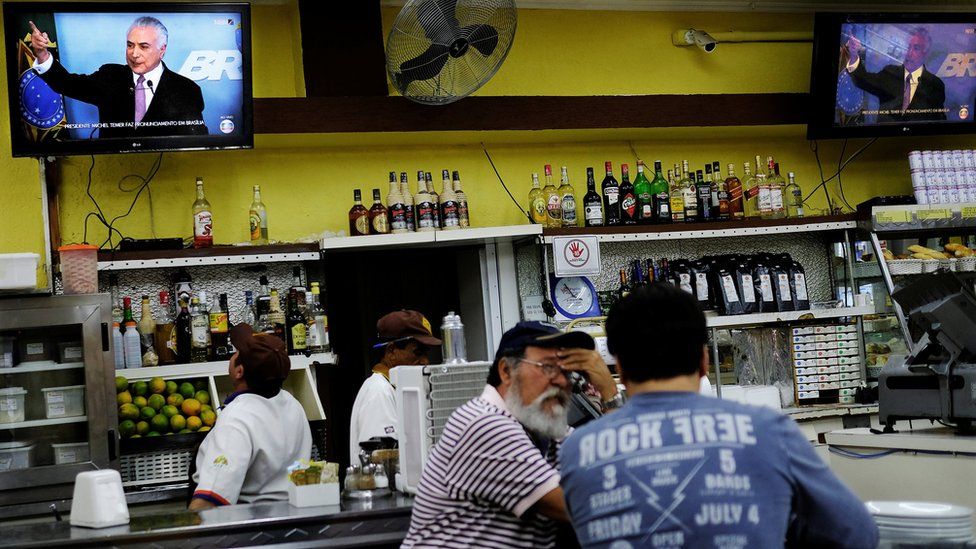 A worker watches television as Brazil's President Michel Temer delivers a speech in Brasilia