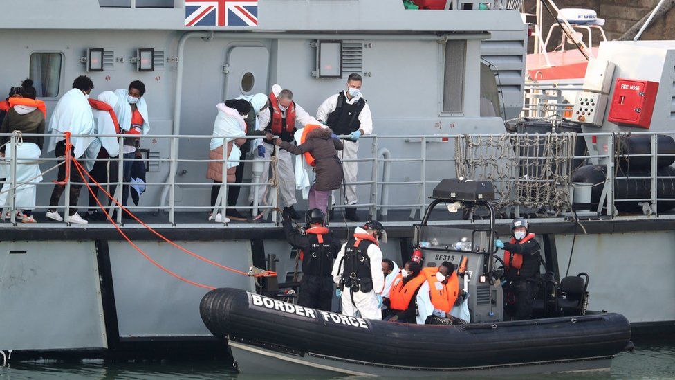 A group of people, thought to be migrants, disembark the deck of HMC Seeker, as they climb aboard a Border Force rib at Dover marina