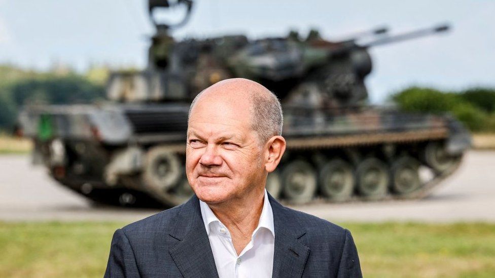 Olaf Scholz stands in front of an anti-air defence system