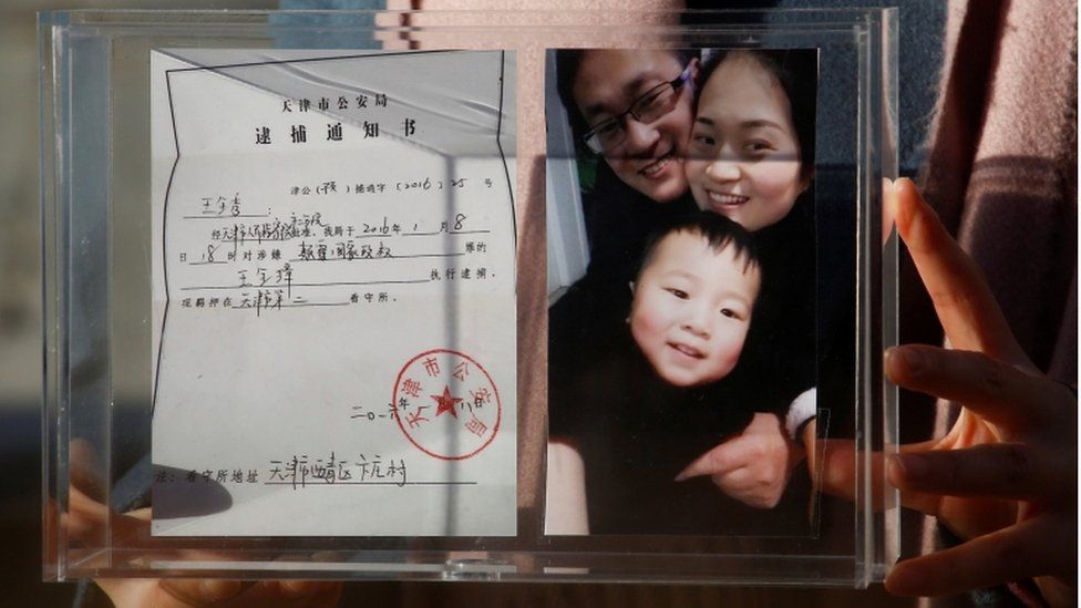 Li Wenzu, the wife of prominent Chinese rights lawyer Wang Quanzhang, holds a box with a family picture and her husband's detention notice, before shaving her head in protest in Beijing, China