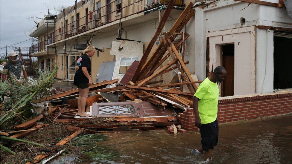People walk through the wreckage of a building in Panama City, Florida, 10 October 2018