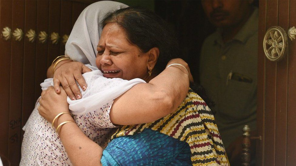 Relatives mourn outside the house, where 11 members of a family were found dead in Delhi.