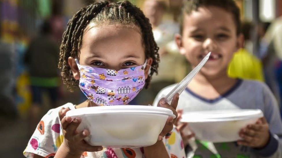 Children from the Favela Aglomerado da Serra receive donation meals on May 20,