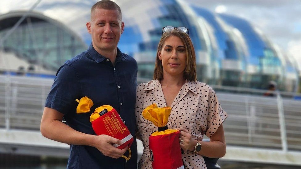 A man and a woman each hold a small red throw-bag