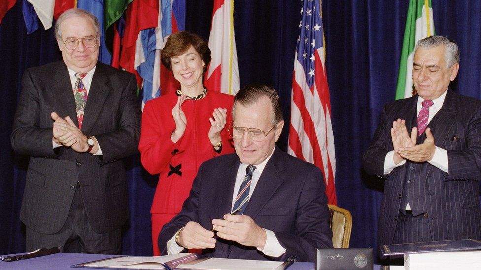 US President George Bush caps his pen after signing the North American Free Trade Agreement at the Organization of American States headquarters, 17 December 1992, in Washington D.C.. Looking on are Mexican Ambassador Gustavo Petricioli (L), US Trade Representative Carla Hills and Canadian Ambassador Derek Burney (R)