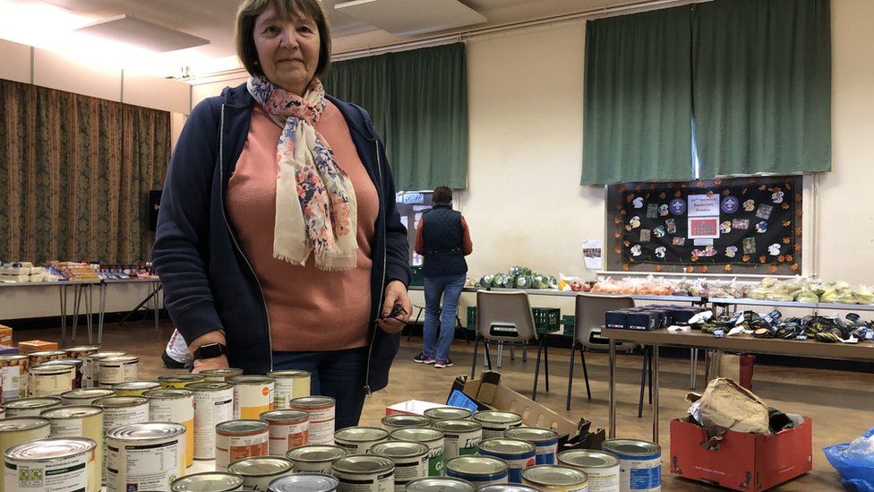 A woman standing behind a table of food in a church hall