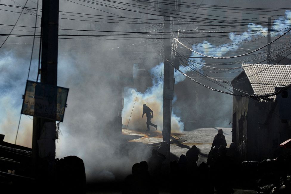 Demonstrators run amid tear gas during clashes with police over a controversial new coca market that coca growers want to shut down as they consider it illegal, in La Paz, Bolivia, 3 August 2022.