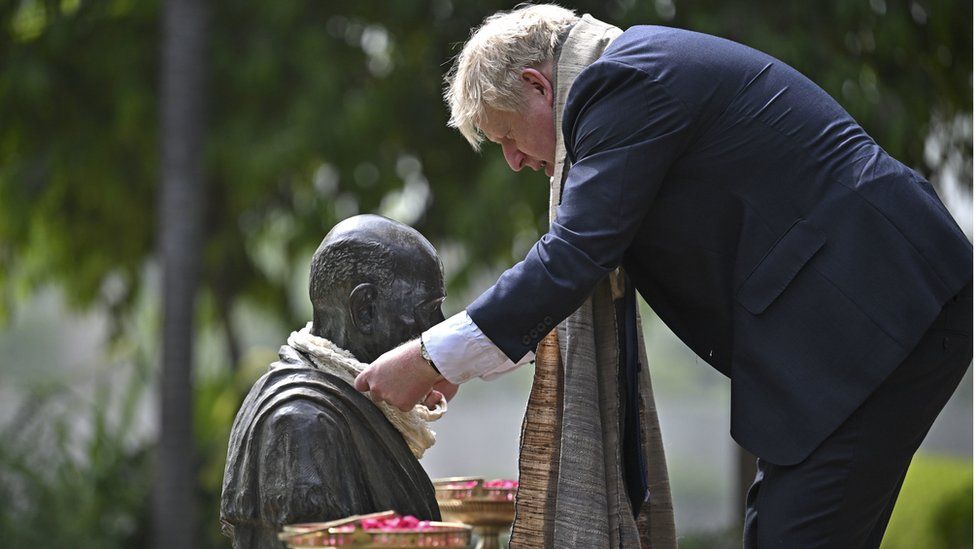 Prime Minister Boris Johnson places a garland on the statue of Mahatma Gandhi