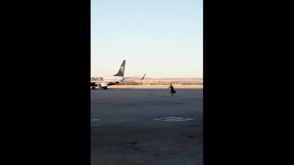 Man alone on tarmac running towards plane