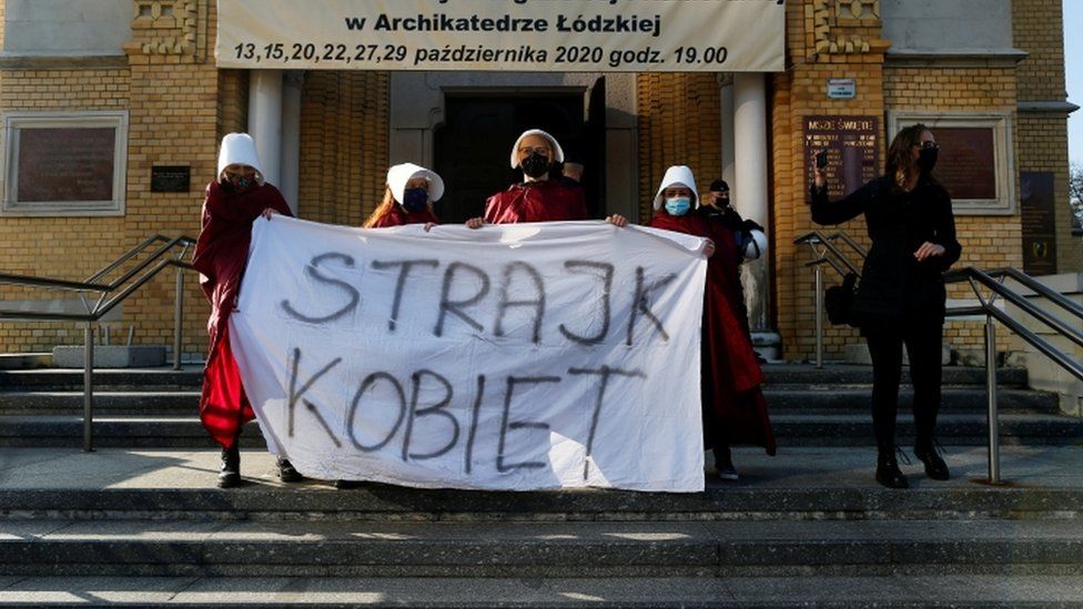 Protesters hold a banned saying "women's strike" outside a cathedral in Lodz, Poland