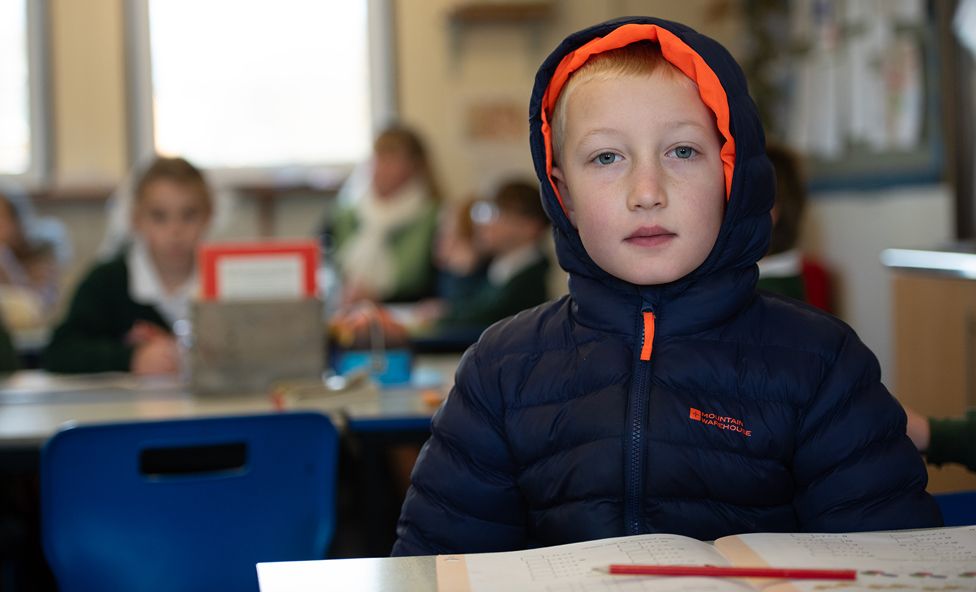 Sebastian, 8, wears an overcoat in the classroom
