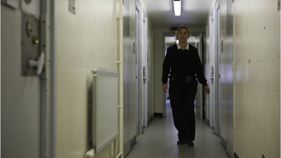 A female prison officer walks down the corridor of a prison's residential wing