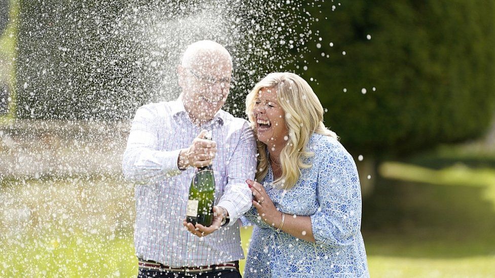 Joe and Jess Thwaite spray a bottle of champagne