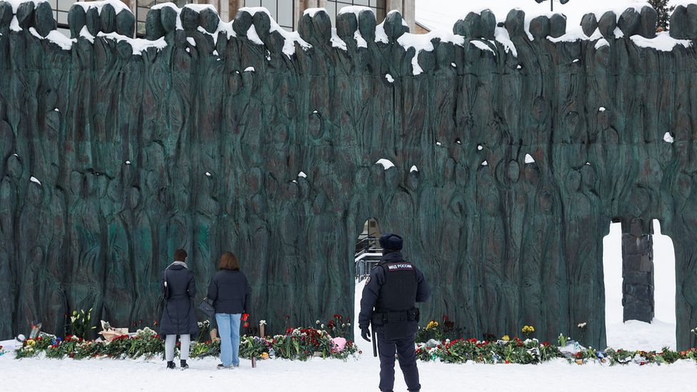 Police officer stands guard as people lay flowers to at the Wall of Grief monument in tribute to Alexei Navalny