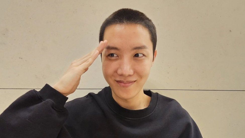 J-Hope with a buzzcut saluting.