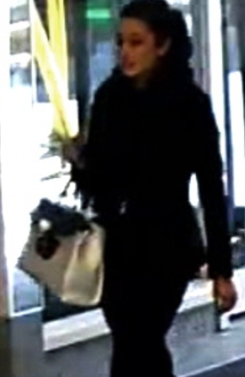 CCTV image of a woman walking with a handbag on her right arm