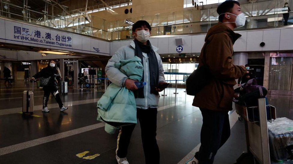 Travellers walk with their luggage at Beijing Capital International Airport, Beijing