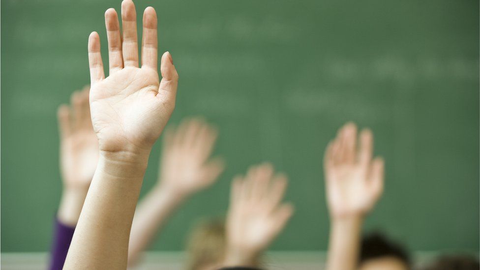 childrens' hands up in classroom