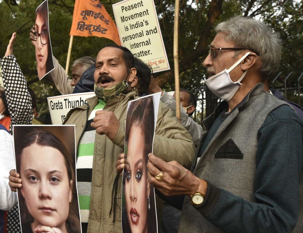 Demonstrators holding pictures of Greta Thunberg and Rihanna with a sign saying 'Peasent movement is India's personal and internal matter'